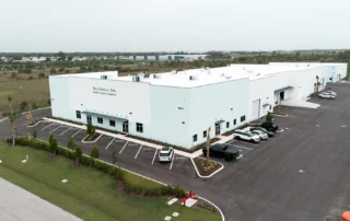 Aerial view of a white Solid Surface Tops manufacturing facility with a landscaped parking lot and loading doors