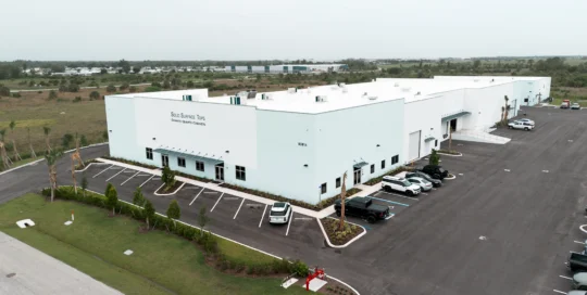 Aerial view of a white Solid Surface Tops manufacturing facility with a landscaped parking lot and loading doors