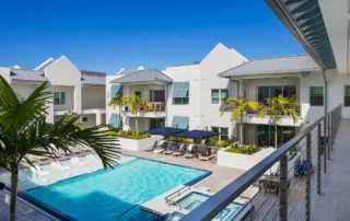 The Mark Luxury Condominiums courtyard pool with lounge chairs, palm trees, and white buildings with metal roofs, seen from