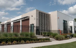 Completed Pine Street storage warehouse with brown roll-up doors, black louvered panels, fencing, and landscaped walkway