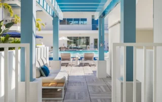 Blue pergola over wood-look tile walkway with lounge seating leading to the pool at The Mark Luxury Condominiums