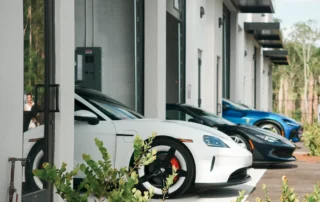 Excalibur Car Condominiums: white, black, and blue sports cars parked at open garage units of a white building with metal