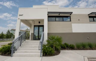 Entrance of Pine Street Storage Warehouse, number 2447, with concrete stairs, metal railings, glass doors and landscaping