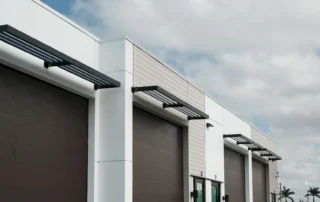 Pine Street Storage Warehouse: white building with brown roll-up bay doors, metal sunshade awnings, and brown entry doors