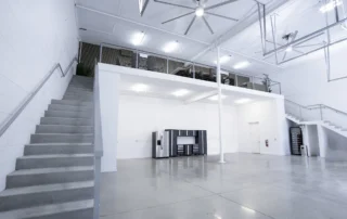 Excalibur Car Condominiums interior with polished concrete floor, concrete stairs to a mezzanine lounge, and garage cabinets