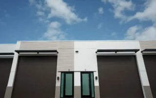 Exterior of Pine Street Storage Warehouse units 8 and 9 with large brown roll-up doors, glass entry doors and metal awnings
