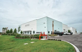 Completed white industrial building with Solid Surface Tops signage, 8381A, landscaped lawn, palms and paved parking lot