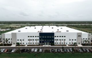 Aerial view of the Safa Goods Distribution Center, a large white building with a navy entrance, palm trees and a full