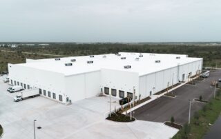 Aerial view of Safa Goods Distribution Center, a large white warehouse with loading docks, trucks, and a landscaped parking