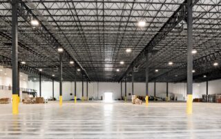 Interior of completed Safa Goods distribution center: open warehouse with steel trusses, polished floor and mezzanine stairs