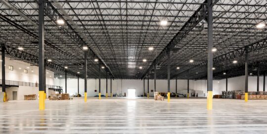 Interior of completed Safa Goods distribution center: open warehouse with steel trusses, polished floor and mezzanine stairs