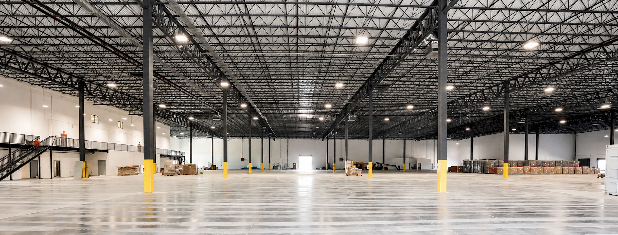 Interior of completed Safa Goods distribution center: open warehouse with steel trusses, polished floor and mezzanine stairs