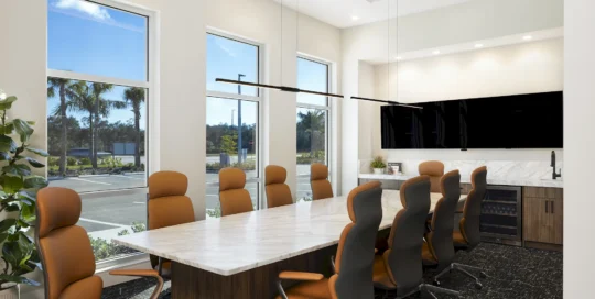 Conference room with marble table, tan high-back chairs, wall display, wet bar and windows facing palm trees in GCM's office