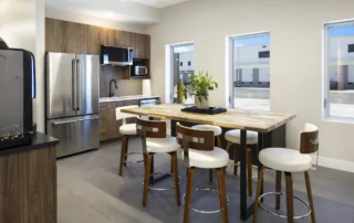 Office break room with wood cabinets, stainless steel appliances and a butcher-block high-top table with white stools